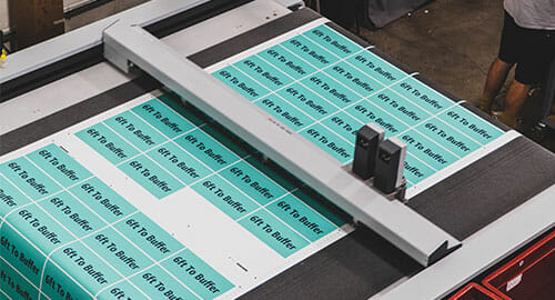 Zund routing machine cutting teal printed labels.