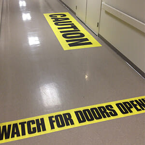 Caution and Watch For Doors Opening floor decals installed in the hallways of Banner Health