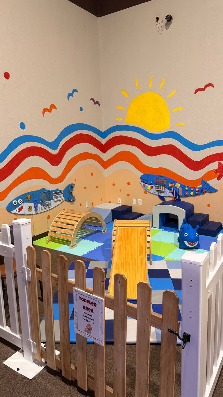 Toddler soft play area with climbing arch, slide, and sensory wall at Central Arkansas Inflatables