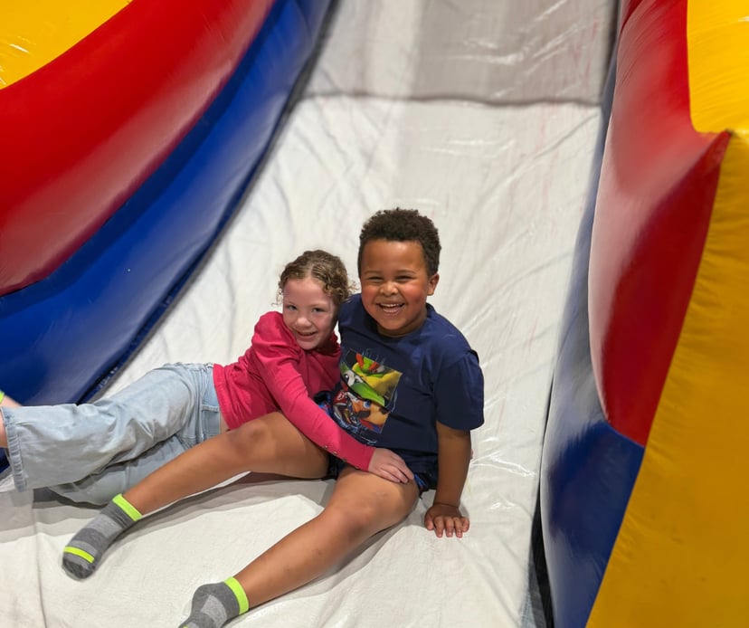 Kids sliding down a big indoor inflatable slide during open play in Bryant, AR