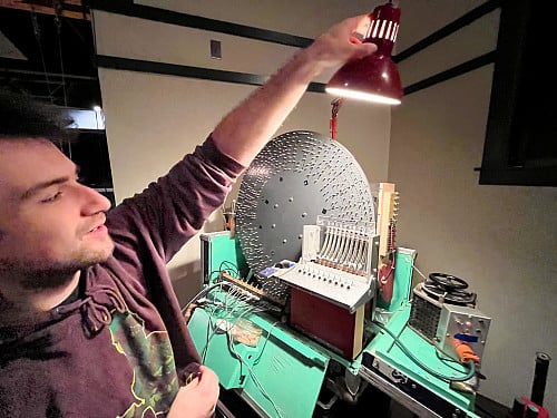 Person holding lamp near machinery.