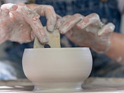 Hands shaping pottery on wheel