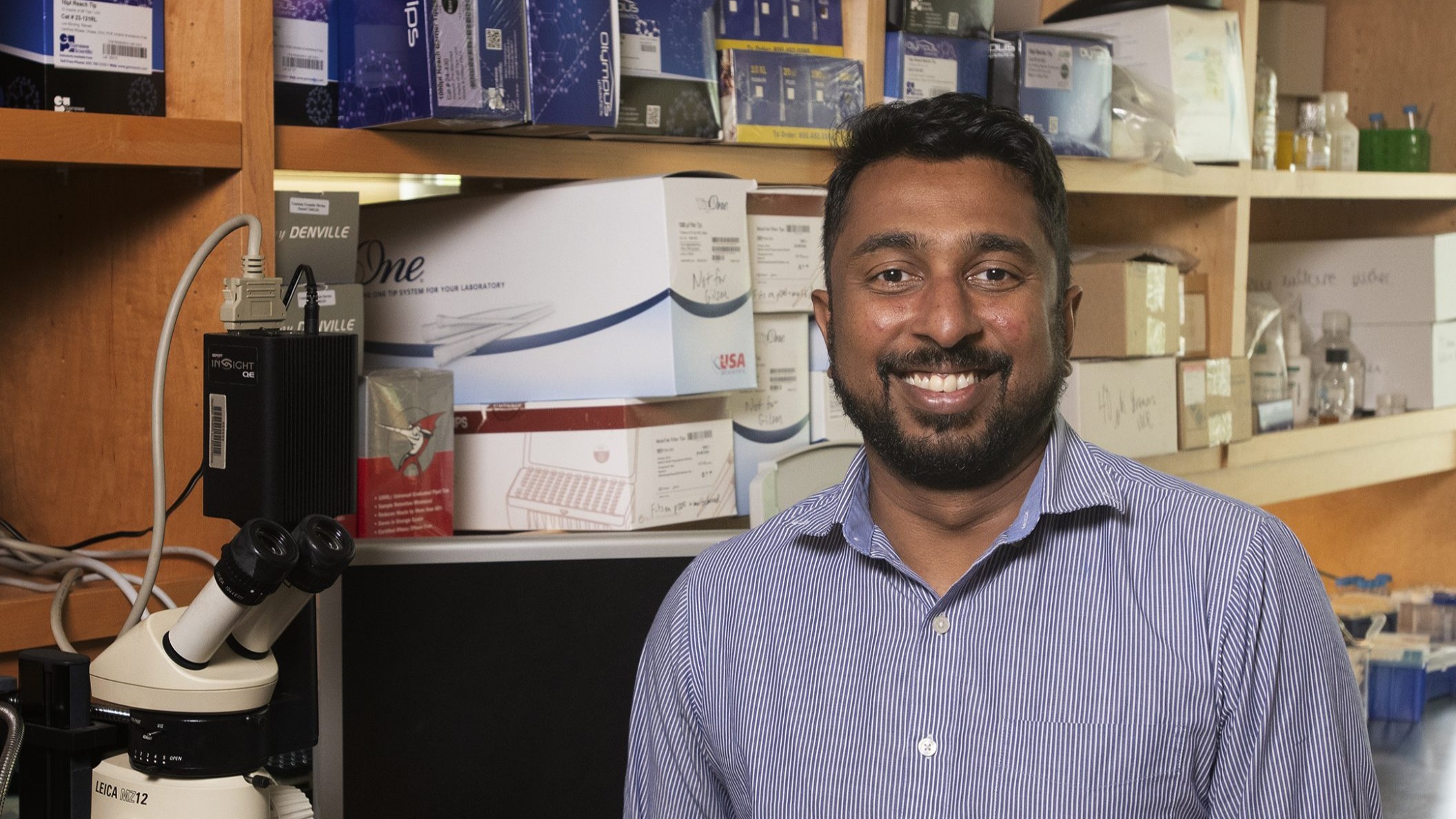 Smiling man in laboratory setting.