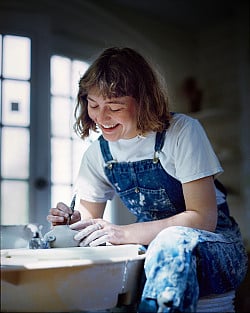Person sculpting pottery on wheel.