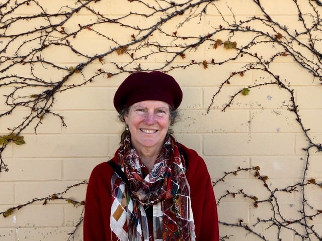 suzanne with a beret in front of a wall with vines