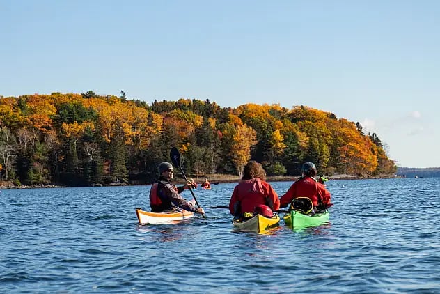Kayakers enjoying autumn scenery on water