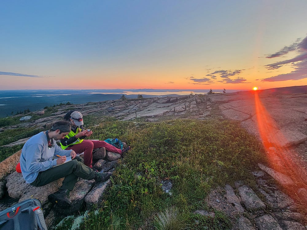 Researchers observing sunset on mountain