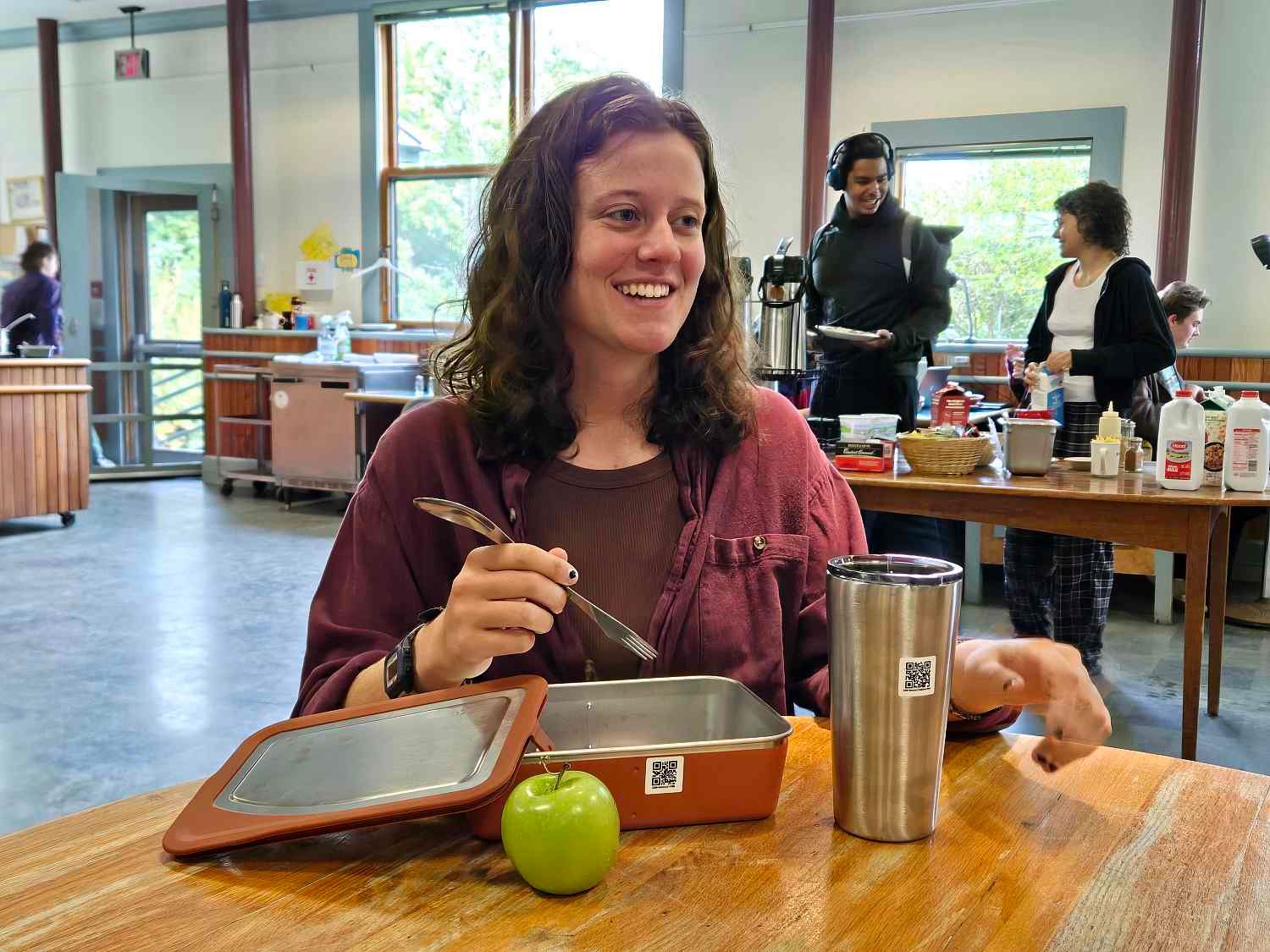 A student displays COA's new reusable to-go ware in Take-A-Break, the college's dining hall.