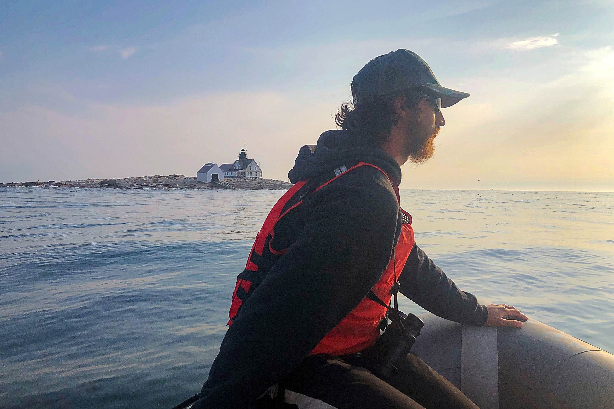 student on rigid hull inflatable on the water with island and lighthouse in background