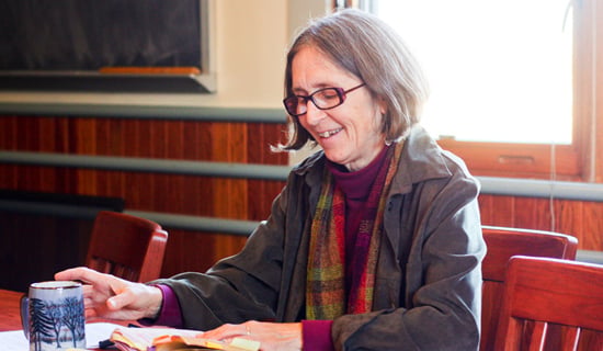 karen at table with coffee mug and a book