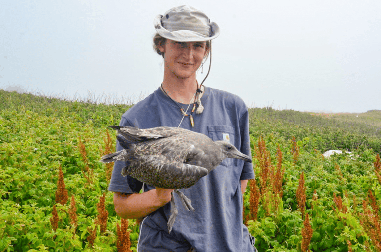 Person holding a bird outdoors.