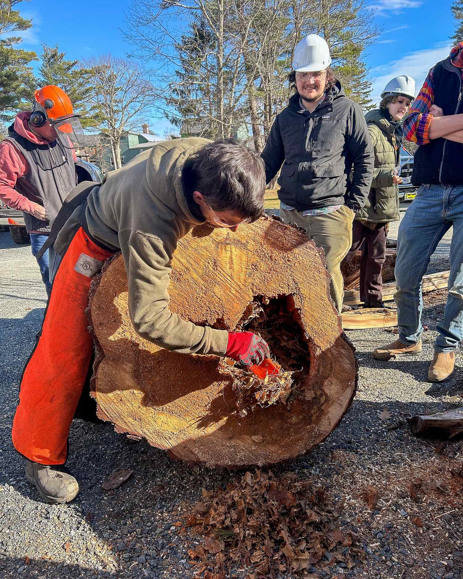 Man carving wood log outdoors.