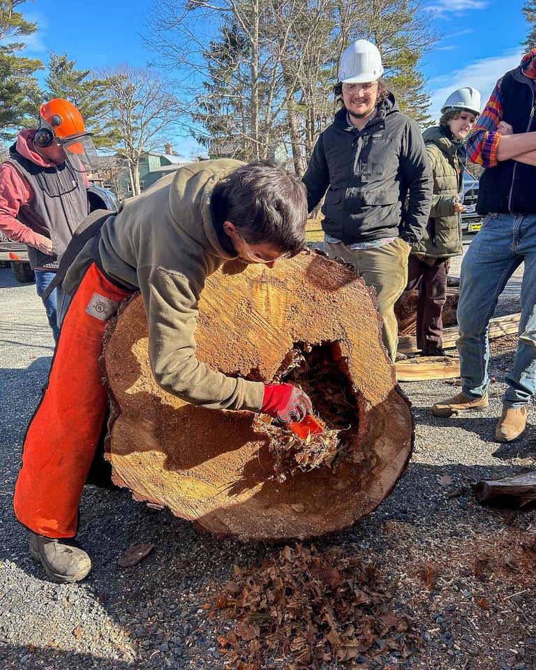 Man carving wood log outdoors.