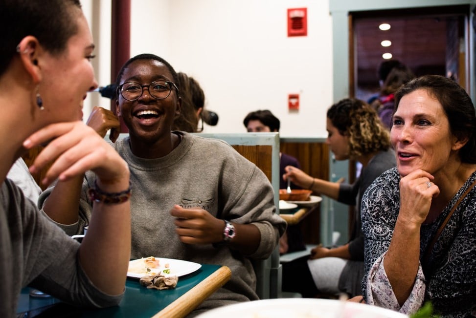 several people laughing and talking together in the dining hall