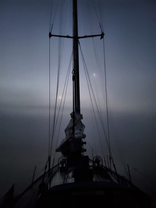 Sailboat in foggy twilight atmosphere
