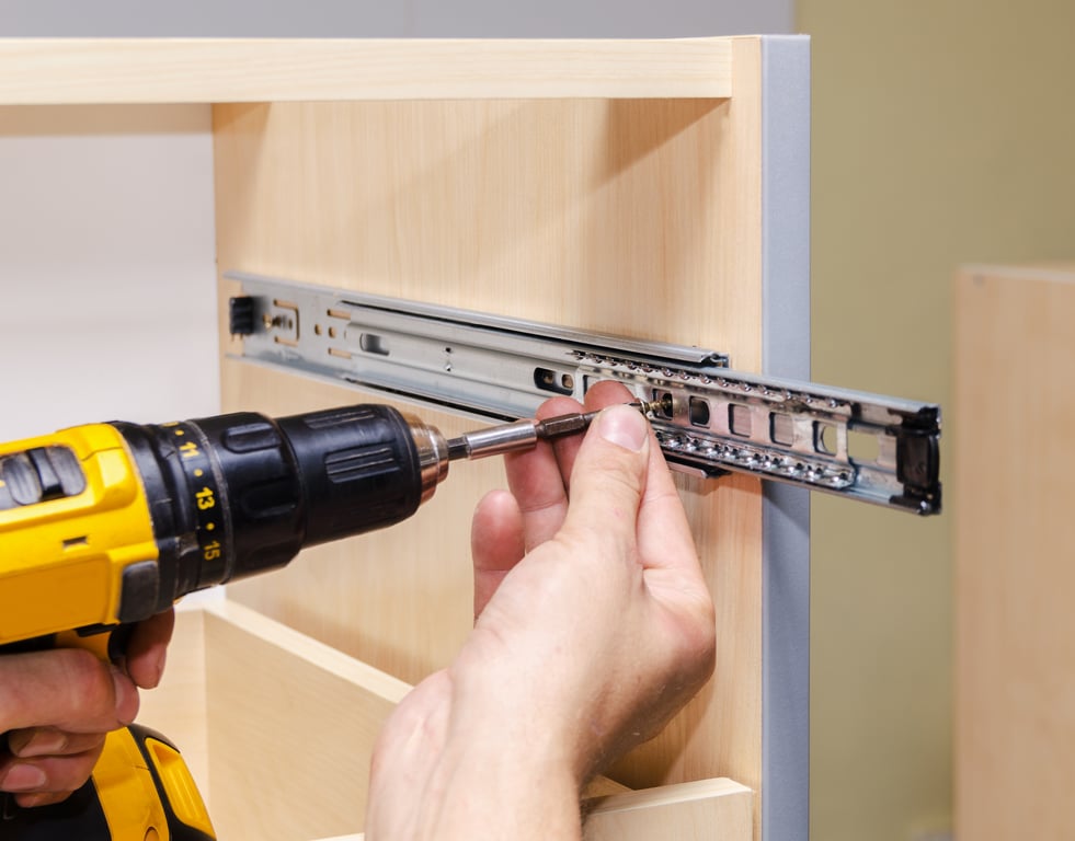 Installer securing a drawer slide during custom closet installation