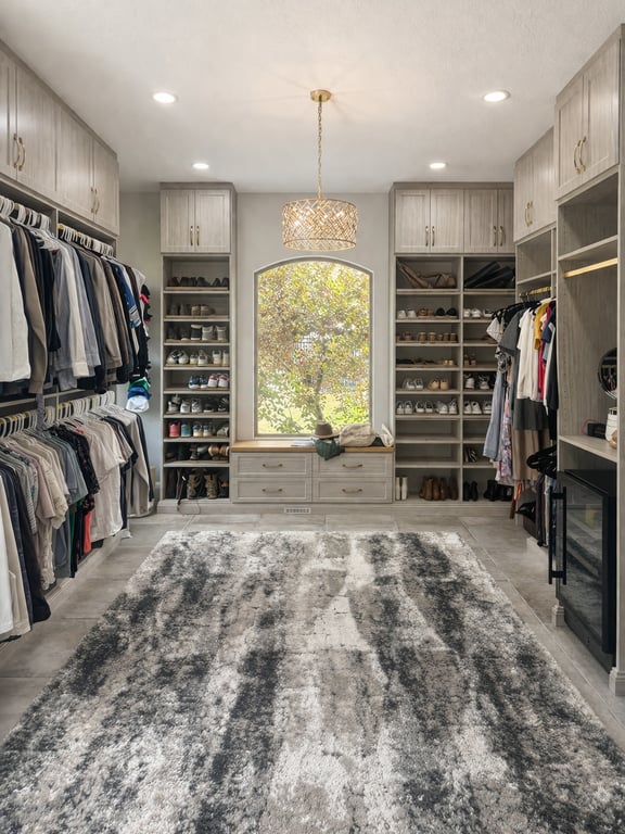 A spacious walk-in with custom cabinetry, chandelier lighting, and a window seating nook.