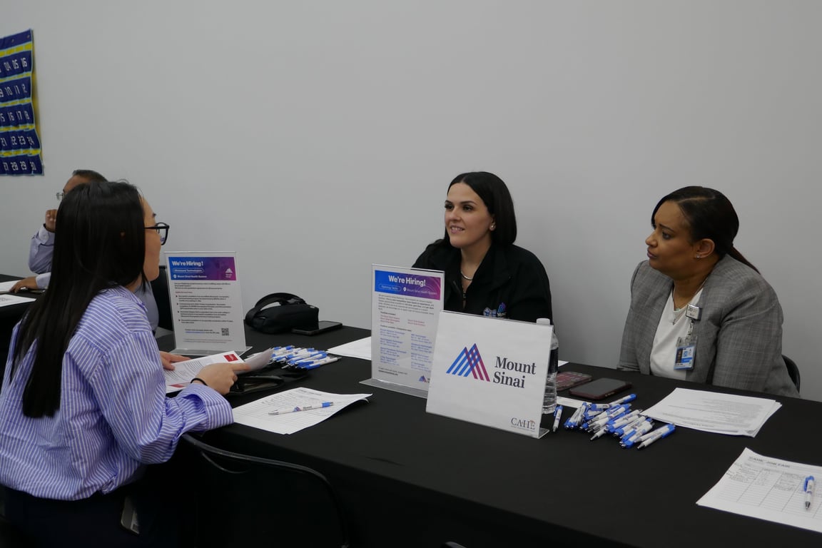 CAHE students speaking with hiring partners at a campus job fair table.