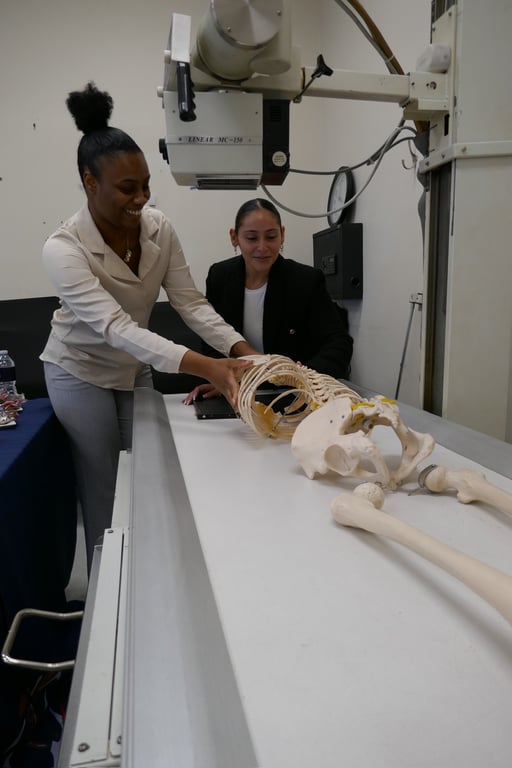 Two people position an anatomical skeleton model on a radiographic table under a LINEAR X-ray tube assembly.