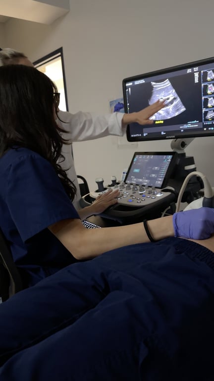 A sonography student practices patient scanning with an ultrasound transducer during a lab session.