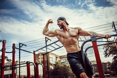Man exercising on outdoor fitness equipment, flexing muscles.