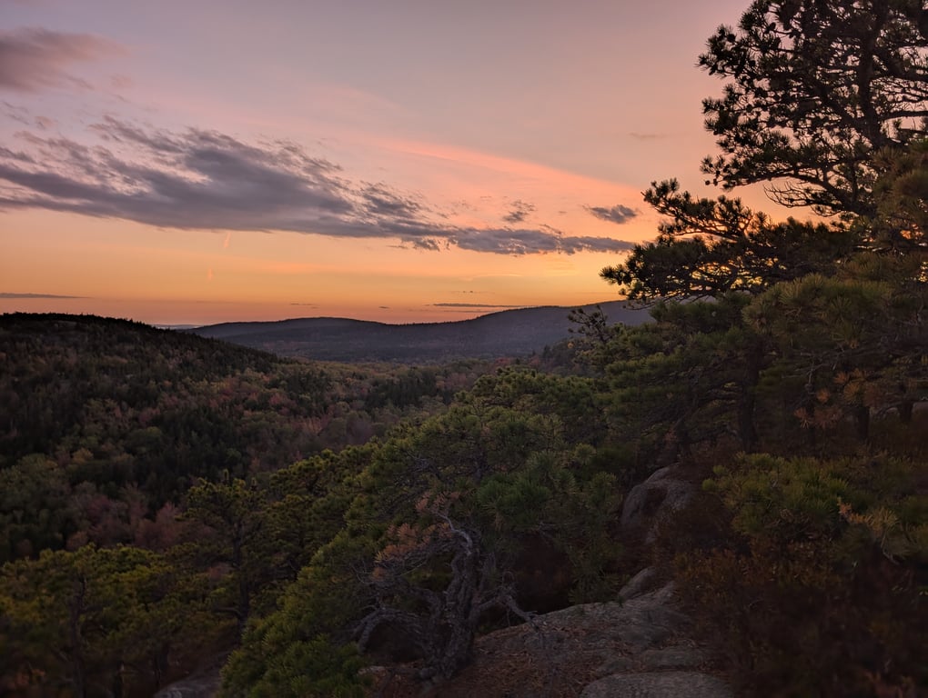 Image with caption 'A soft sunset in the distance, from the top of the Beehive Trail. We made it to the top just as the sun was setting (don't worry, we brought flashlights).'