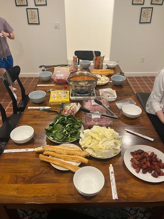 Image with caption 'Hot pot with a smattering of foods to add (alcohol not shown). This hot pot was done more Korean-style, and I was particularly surprised at the Chinese donuts (炸油條) being one of the ingredients that you add to the hot pot as I usually associate that with being a breakfast food paired with soy milk.'