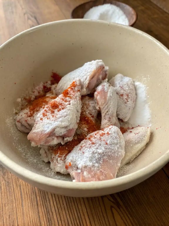 Chicken wings arranged in a single layer in an air fryer basket ready for cooking.