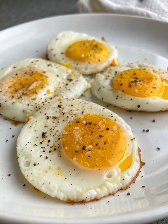 Air fryer eggs served on a plate with avocado toast and fresh tomatoes for a complete breakfast.