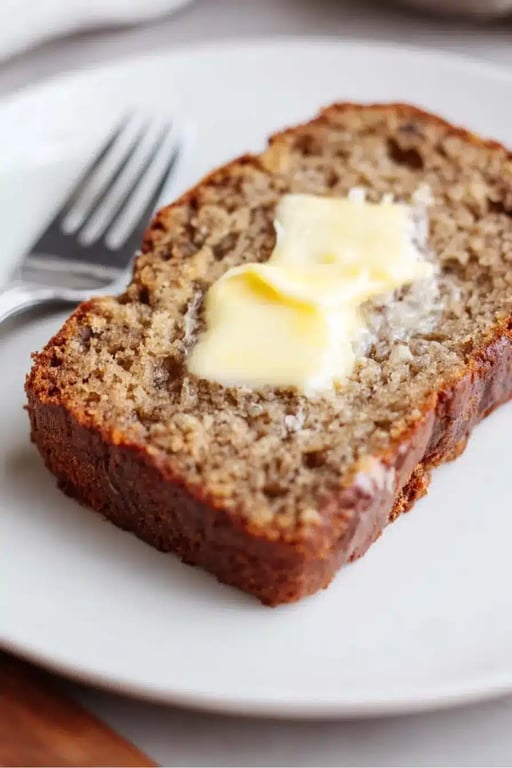 Slice of keto banana bread with melting butter on a white plate