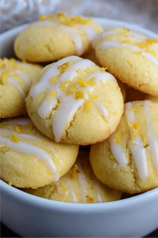 Bowl of soft keto lemon cookies with white glaze and lemon zest