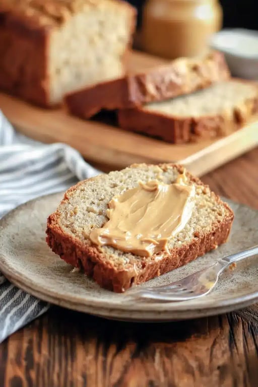 Slice of low carb banana bread with peanut butter on ceramic plate