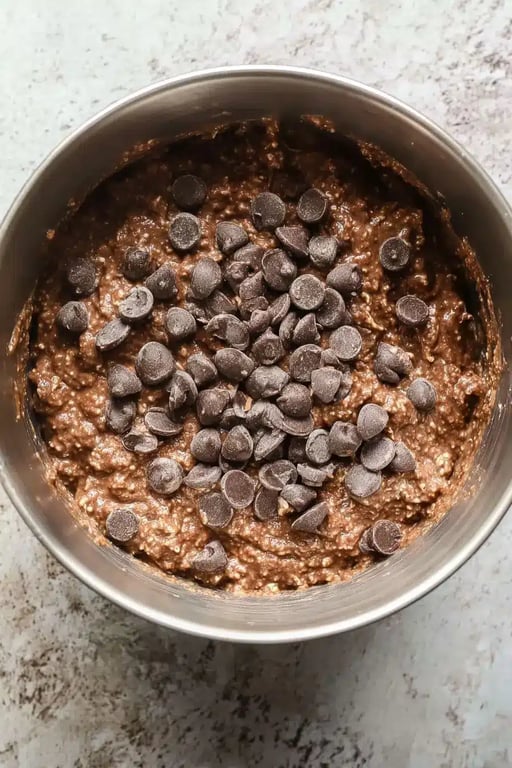 Protein Brownies That Taste Like Fudge and Keep You Full Longer 7 Raw chocolate protein brownie batter topped with dark chocolate chips in a mixing bowl