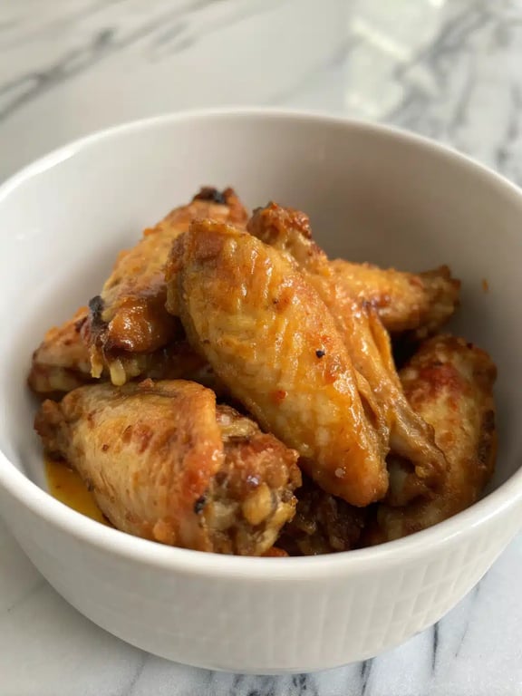 A platter of finished air fryer chicken wings surrounded by celery sticks and dipping sauce