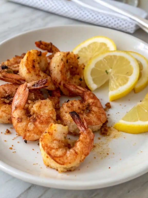 air fryer shrimp plated with lemon wedges and a side salad