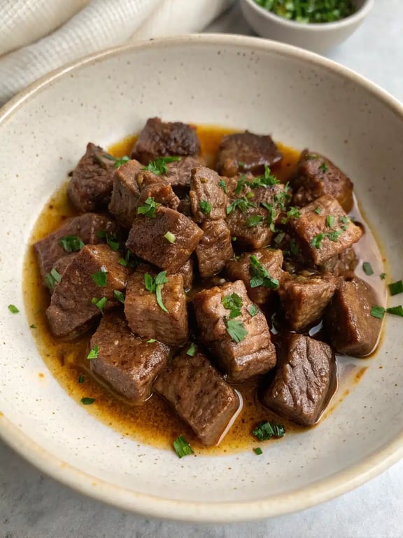 Garlic butter beef bites served over mashed potatoes with a side of green beans, drizzled with sauce