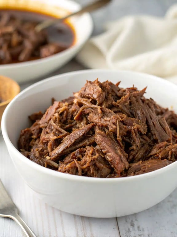 A vibrant spread of slow cooker barbacoa served in tacos, bowls, and with fresh toppings
