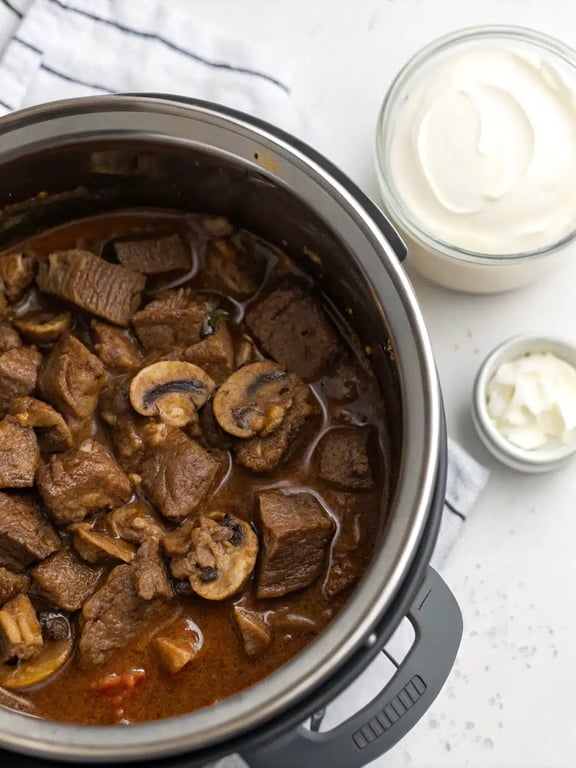 Finished instant pot beef tips with gravy served in a bowl over egg noodles