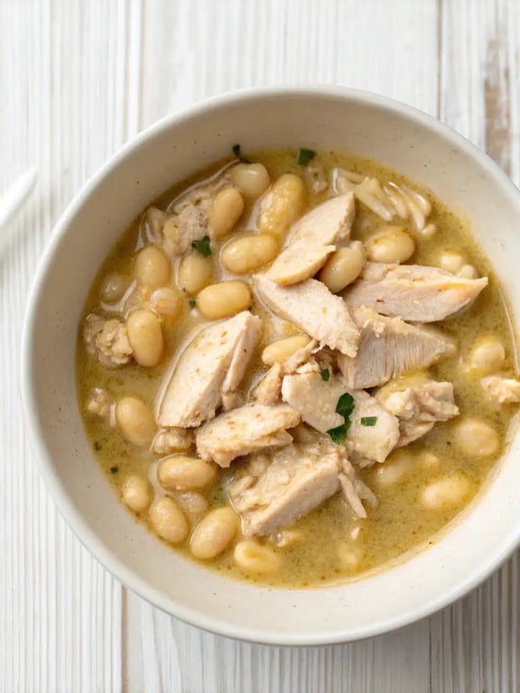 A beautifully served bowl of white chicken chili with colorful toppings like avocado, cilantro, and lime