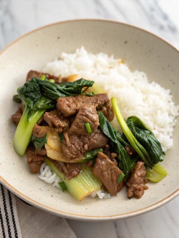 bok choy beef stir fry plated beautifully with white rice and garnishes
