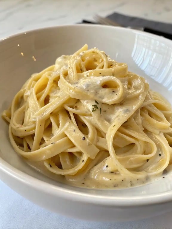 creamy garlic pasta beautifully plated with side salad and bread