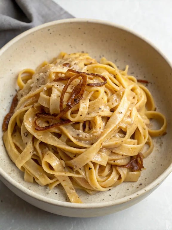 A beautifully plated bowl of vegan onion pasta with a side salad