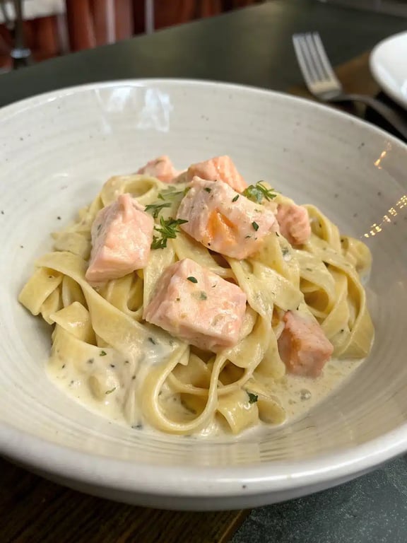 creamy salmon pasta beautifully plated with a side salad and lemon wedge