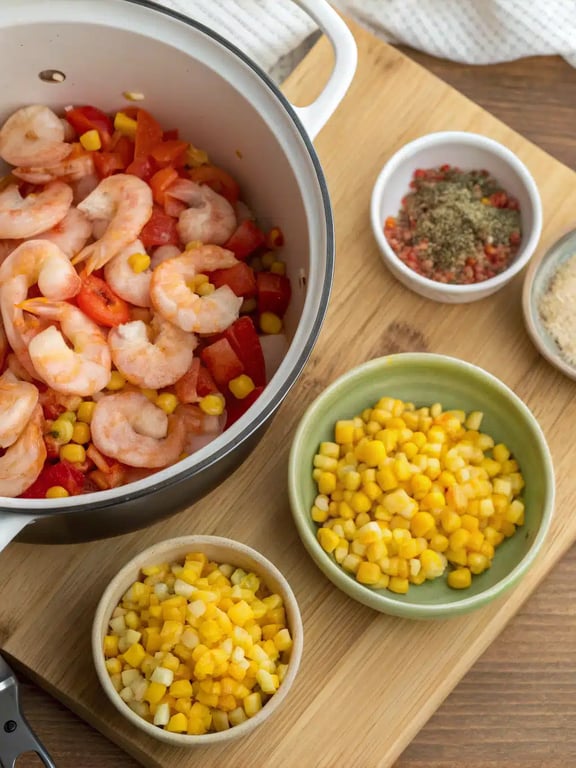 Adding shrimp and corn to the simmering shrimp corn chowder pot
