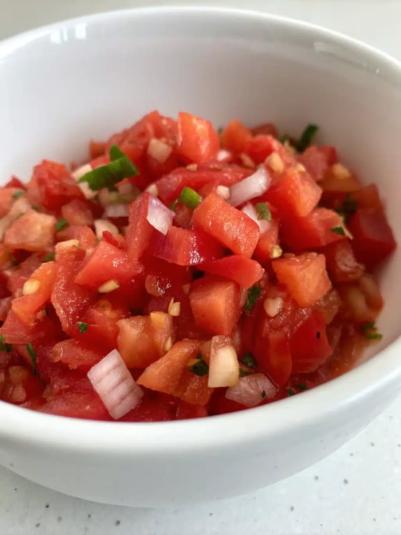 A vibrant bowl of fresh tomato salsa served with tortilla chips and tacos