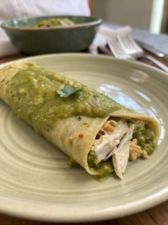 Beautifully plated green chicken enchilada with rice and beans
