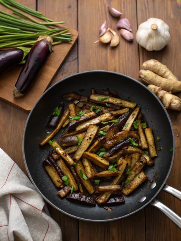 Final step for Chinese eggplant garlic sauce — plated in a bowl with steamed rice and garnished with green onions
