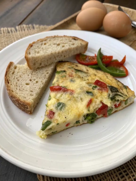 A beautifully plated Mediterranean breakfast recipes frittata wedge with yogurt, toast, and fresh herbs