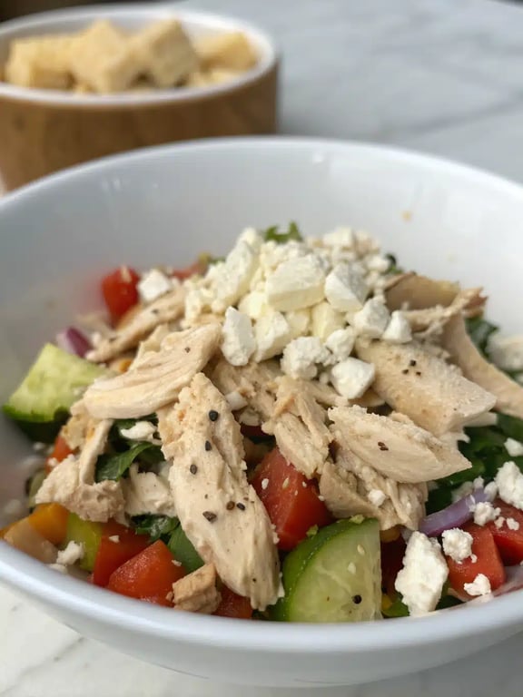 Mediterranean chicken salad served in a bowl with pita bread on the side