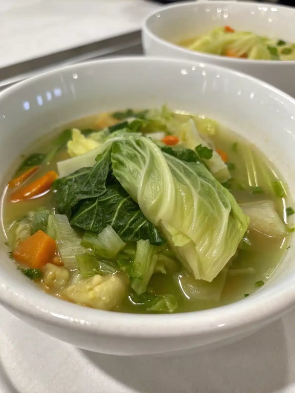 A beautifully served bowl of cabbage soup recipe with crusty bread on the side